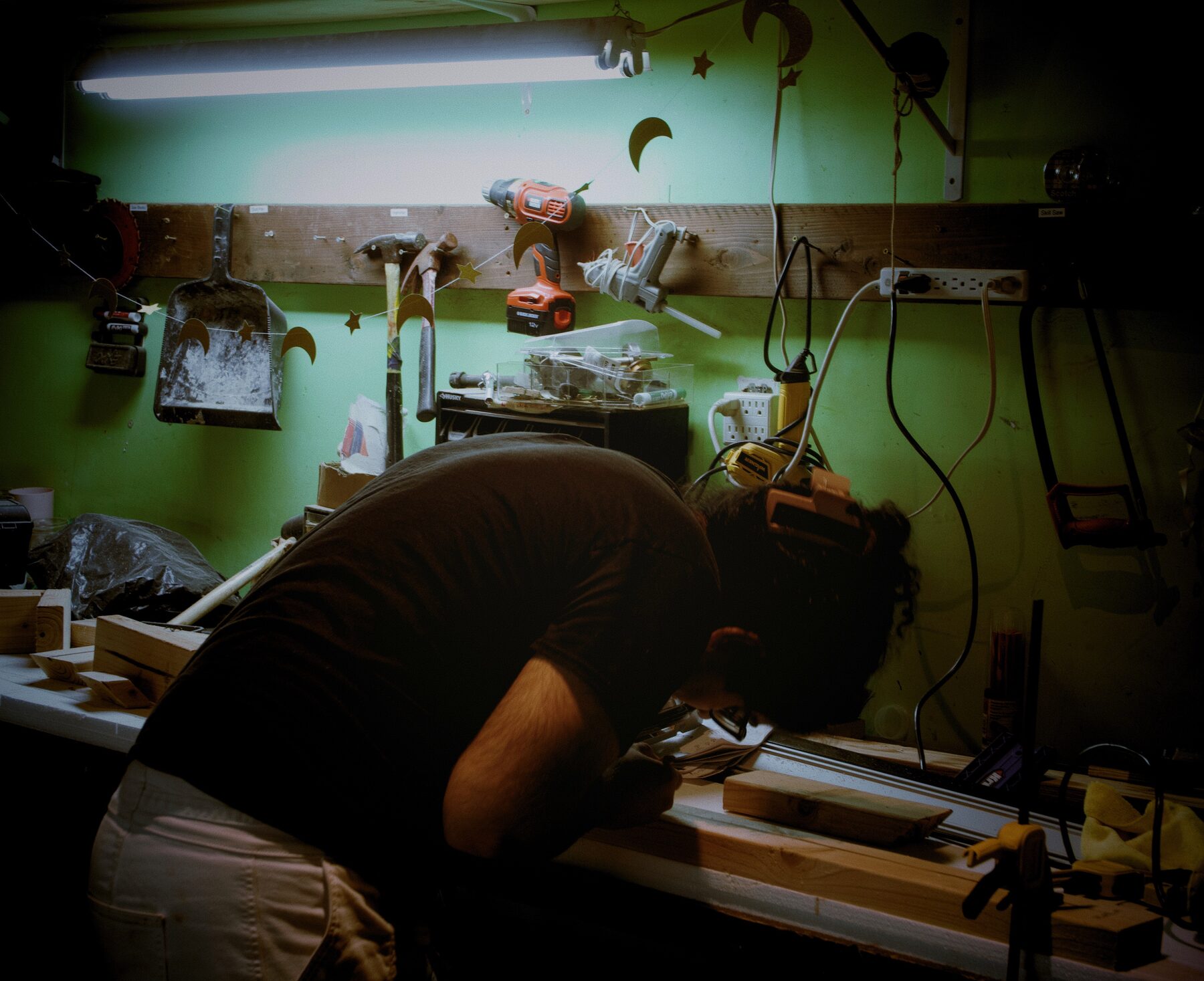 parth bent over a workbench in a green-walled workshop